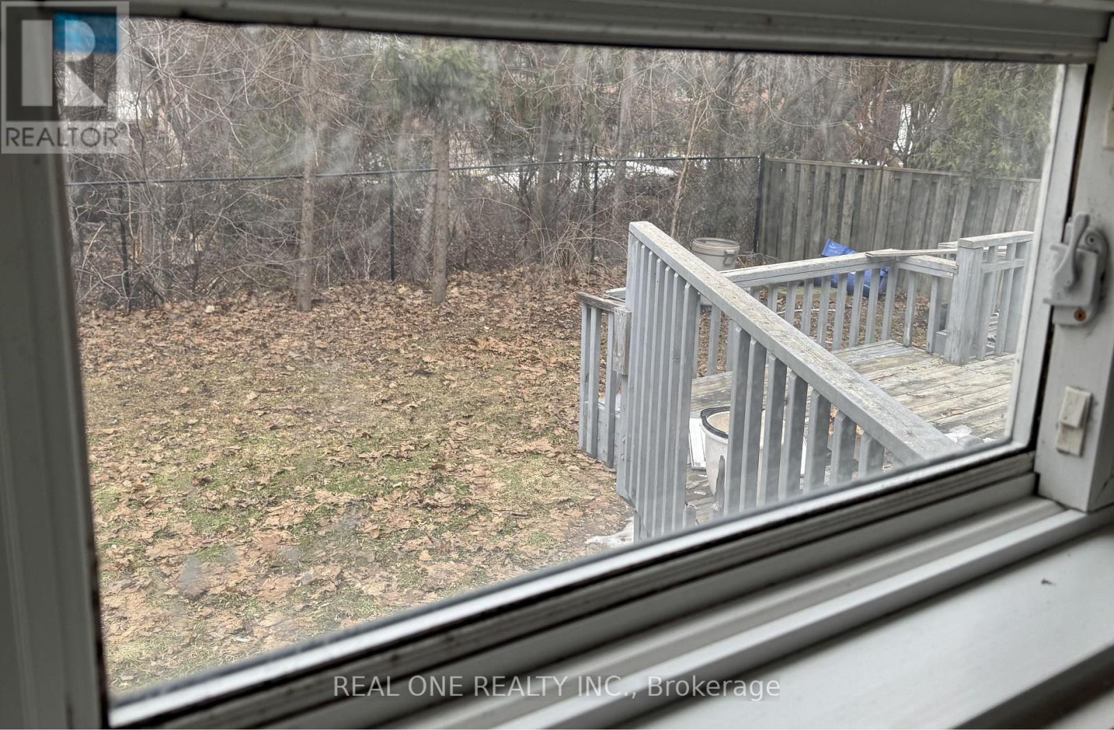 A view from a window looking out to a deck and trees.