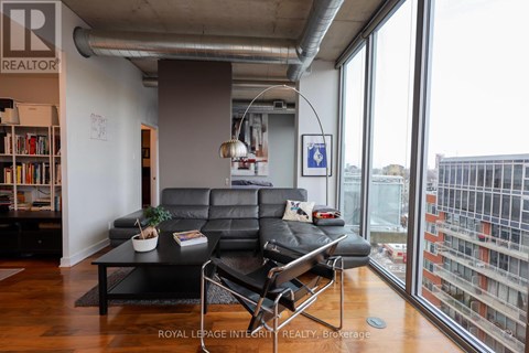 A living room with a black leather couch and a coffee table in front of a large window.