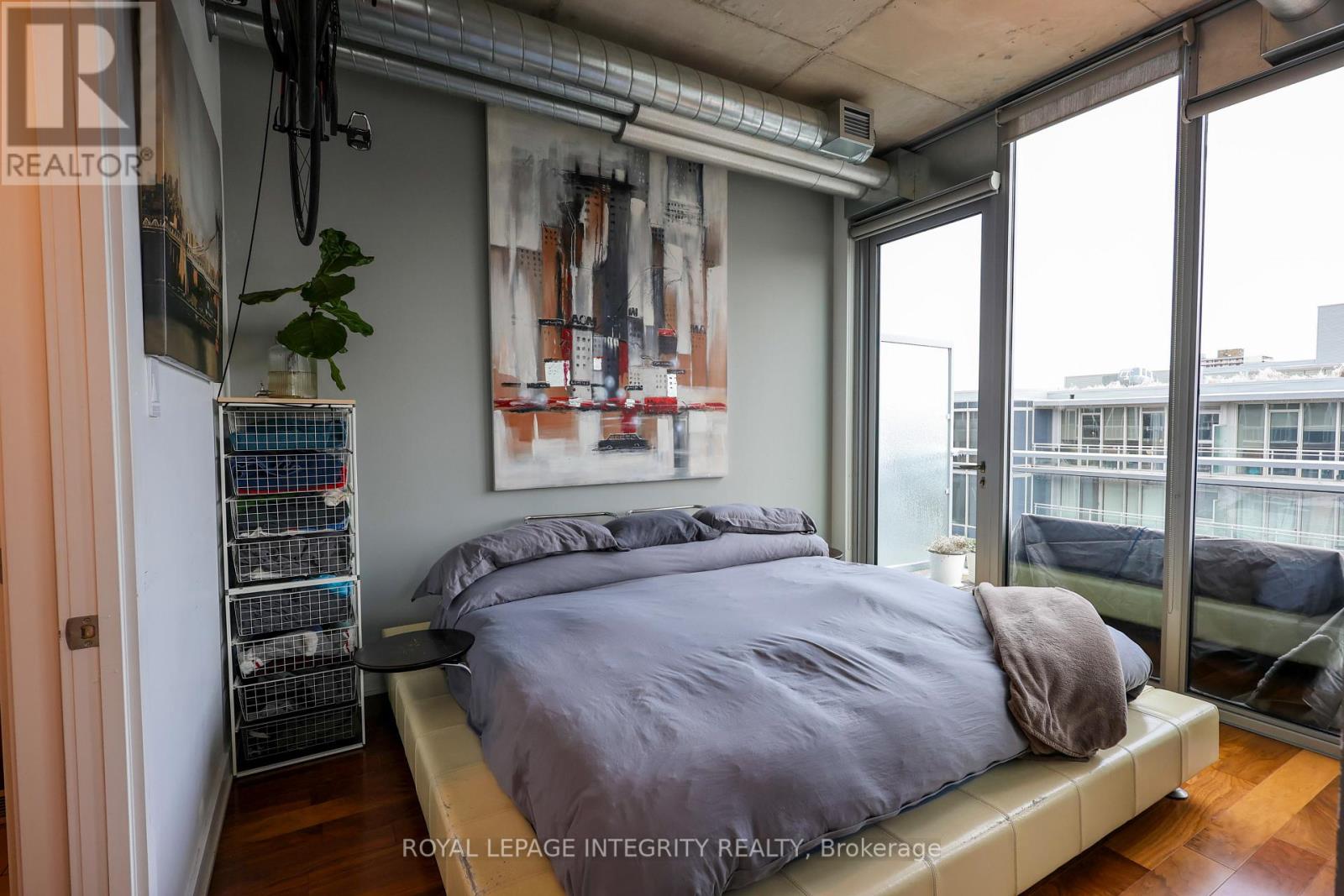 A bedroom with a bed, a plant, and a poster on the wall.