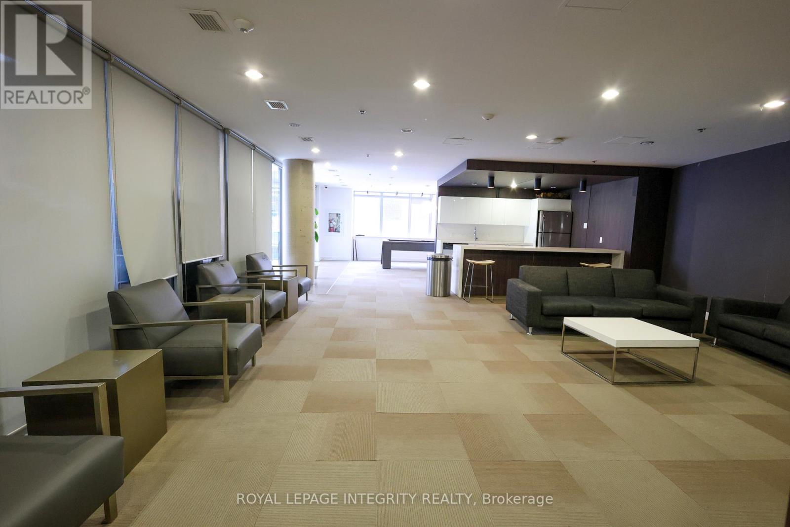 A spacious waiting area with brown tiled floors and grey couches.