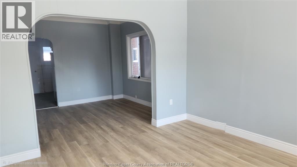 A room with wooden flooring and a grey wall.