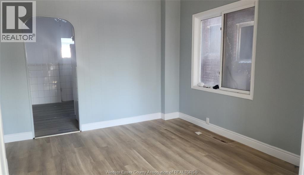 A room with a window and a doorway leading to another room.