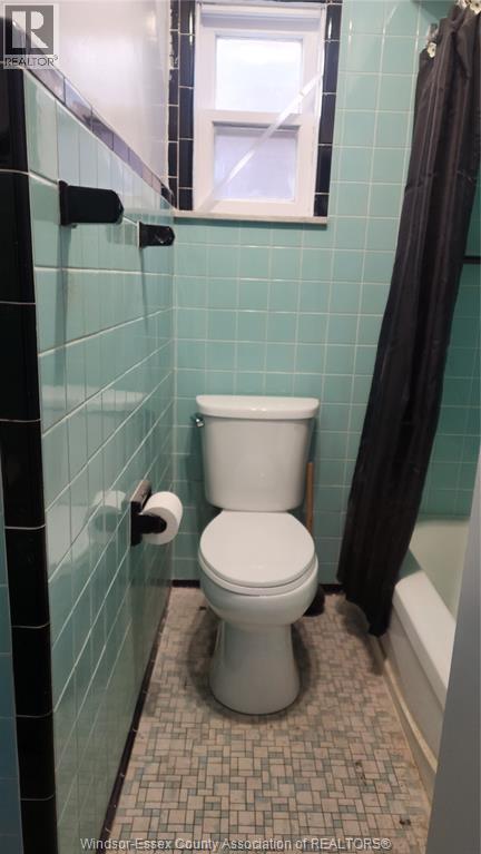 A white toilet in a tiled bathroom.