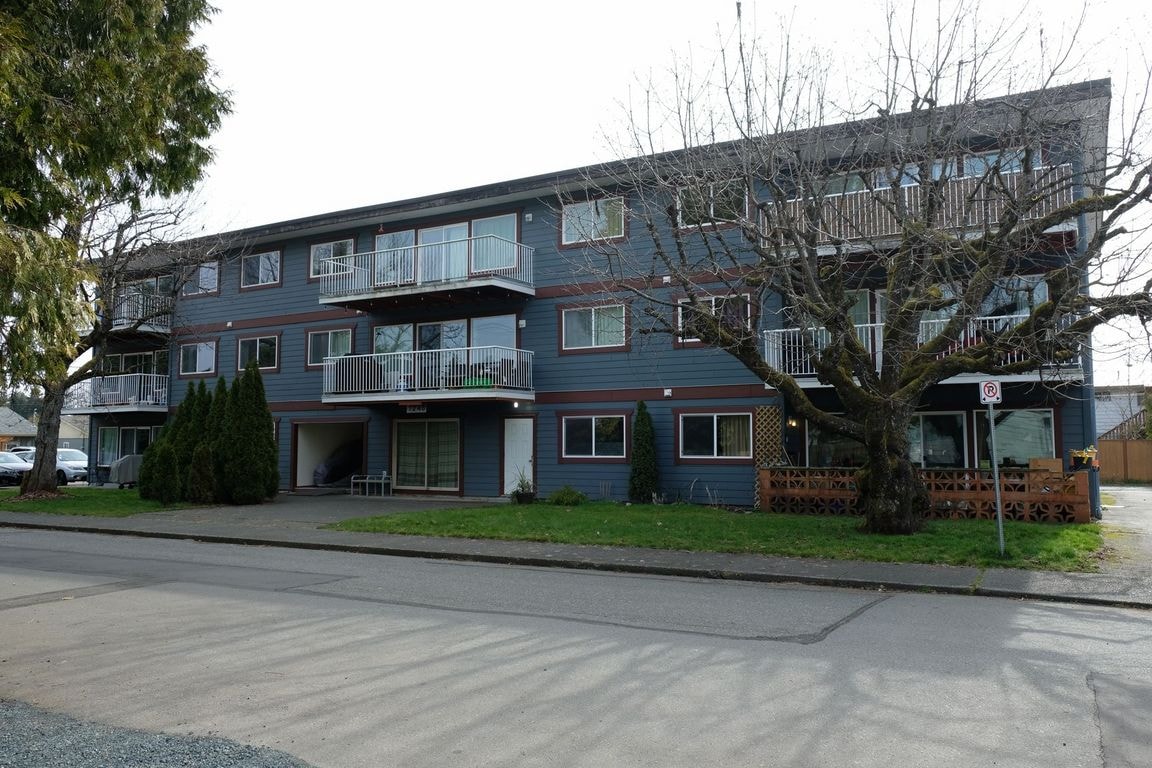 A large apartment building with a tree in front.