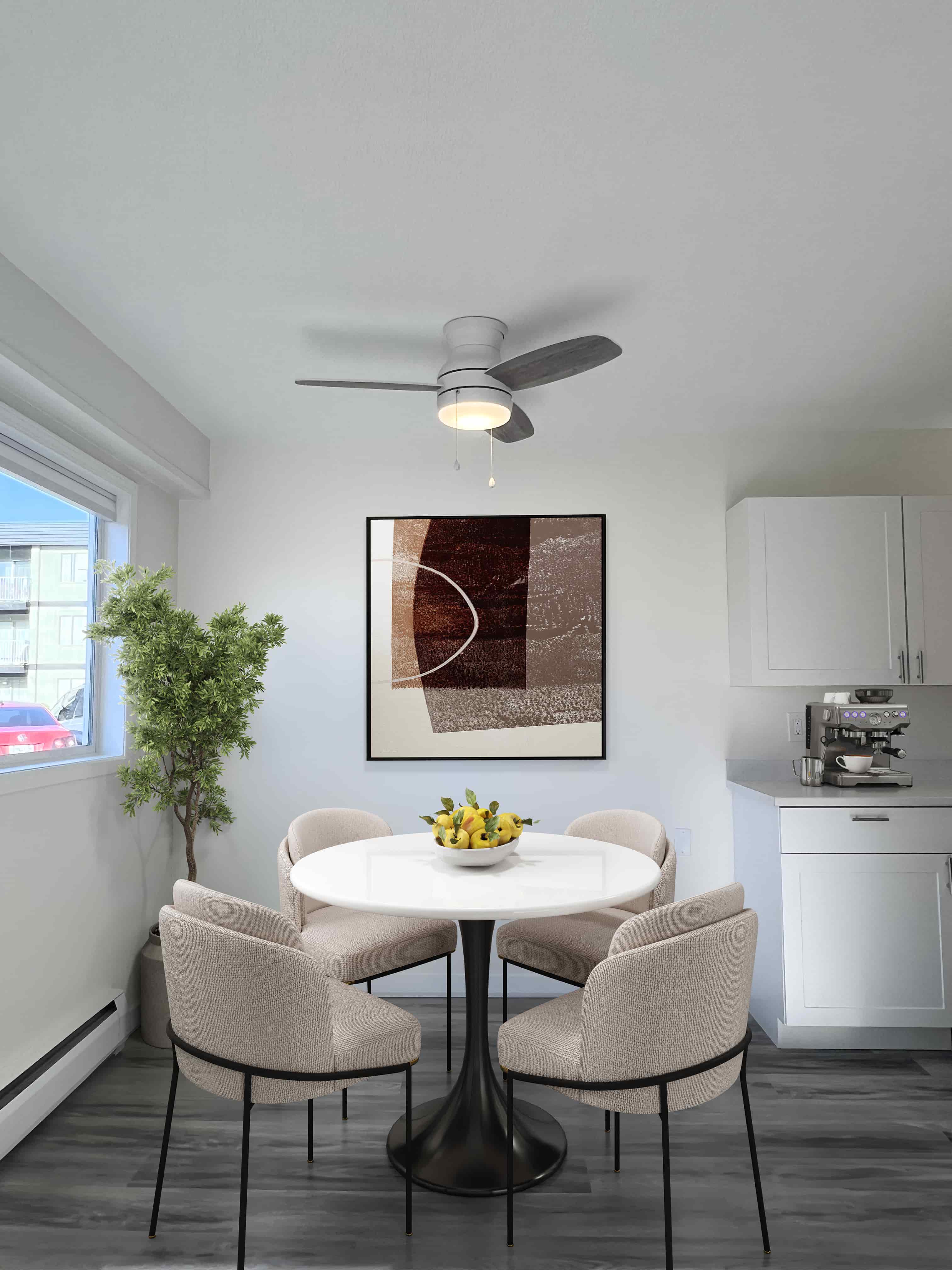 A dining room with a white table and chairs, a ceiling fan, and a painting on the wall.