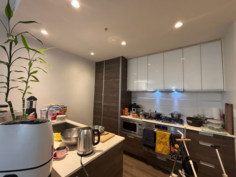 A modern kitchen with white cabinets and a wooden floor.