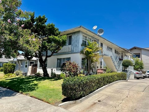A white two-story house with a tree in front.