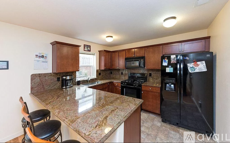 A kitchen with granite countertops and a black refrigerator.