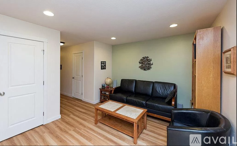 A living room with a black leather couch and a wooden coffee table.