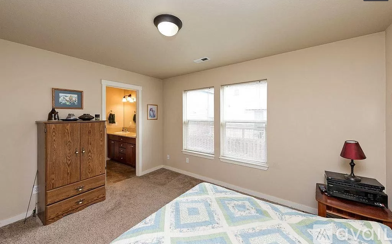 A bedroom with a bed, dresser, and window.