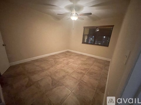 A room with a ceiling fan and a window with blinds.
