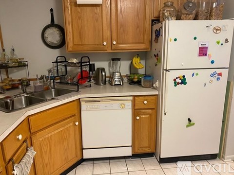 A kitchen with wooden cabinets and a white fridge with many magnets.