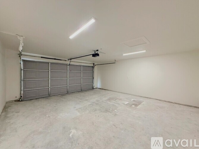 A spacious garage with a grey floor and a grey rolling shutter door.