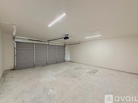 A spacious garage with a grey floor and a grey rolling shutter door.