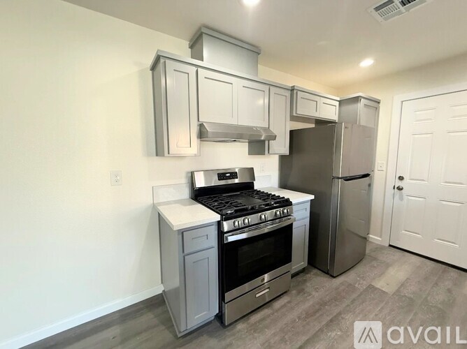 A kitchen with a stove, refrigerator, and cabinets.