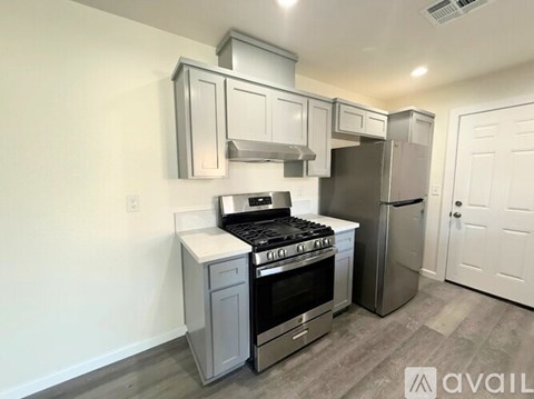 A kitchen with a stove, refrigerator, and cabinets.