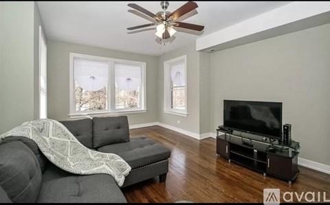 A living room with a grey couch and a black television.