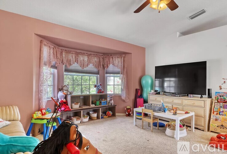 A child's bedroom with a pink wall and a ceiling fan.