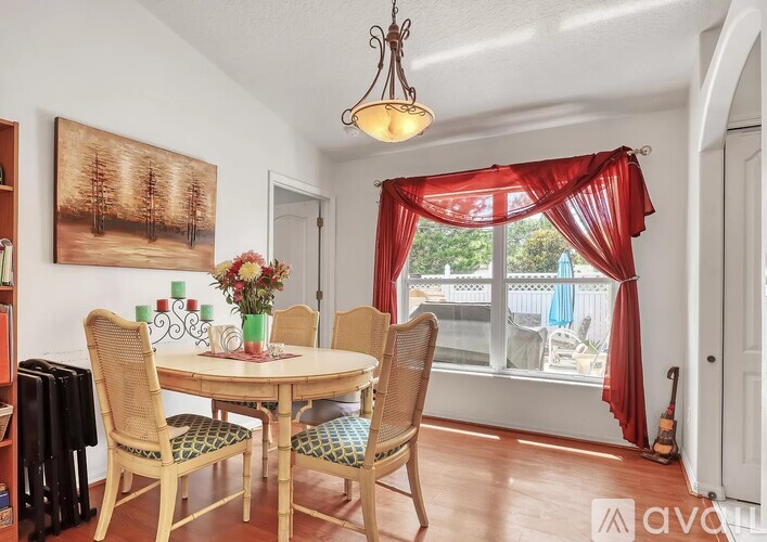 A dining room with a table set for four and a view of the backyard.