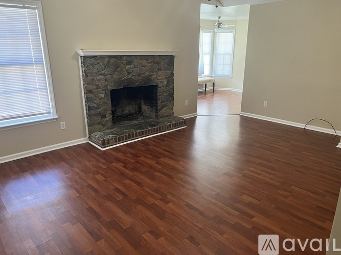 A room with a stone fireplace and wooden flooring.