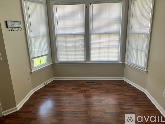 A room with wooden floors and three windows.