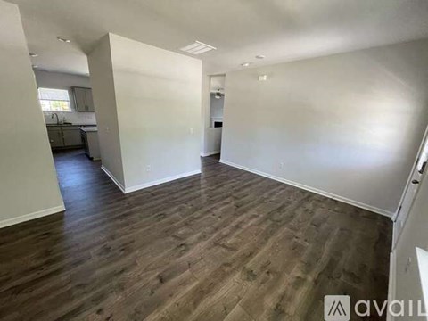 A spacious room with wooden flooring and white walls.