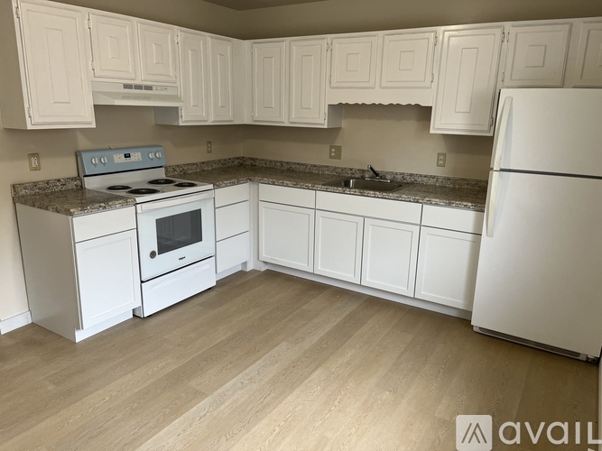 A kitchen with white cabinets and a white refrigerator.