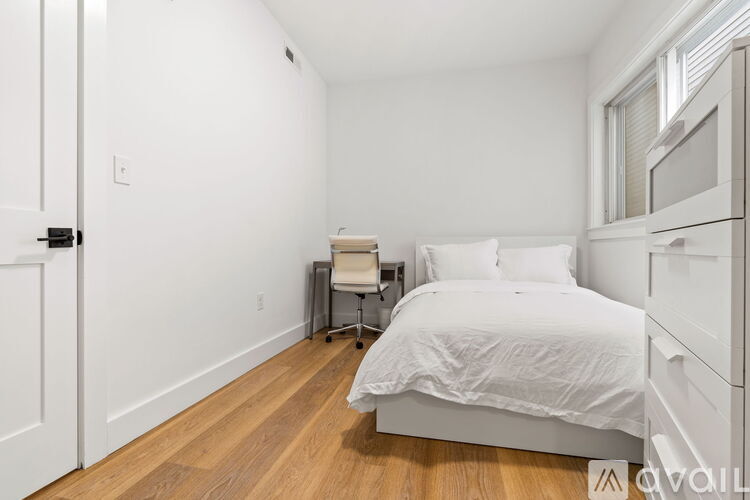 A bedroom with a bed, chair, and desk.
