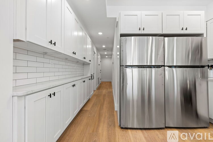 A kitchen with white cabinets and a stainless steel refrigerator.