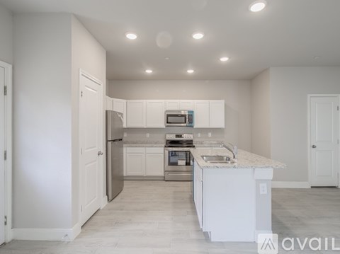 A kitchen with white cabinets and appliances is available for rent.