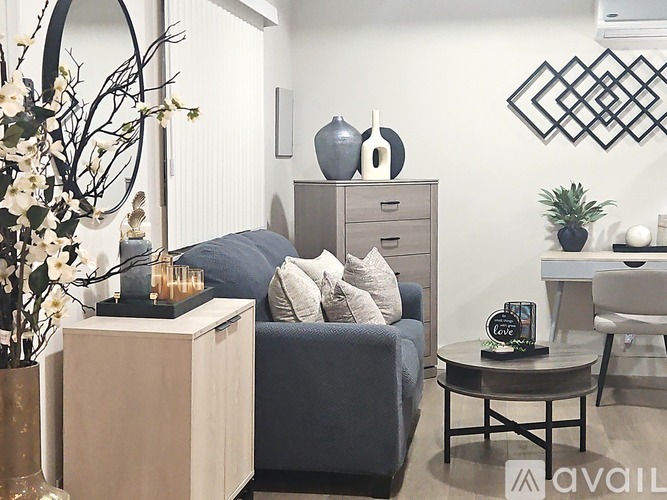 A living room with a grey couch, a coffee table, and a vase of flowers.