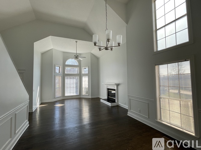 A spacious room with wooden floors and a chandelier hanging from the ceiling.