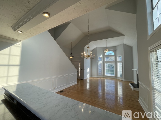 A spacious room with a marble floor and a chandelier hanging from the ceiling.