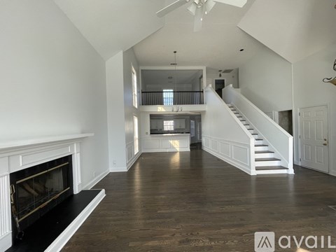 A spacious living room with a fireplace and a staircase leading to the upper level.
