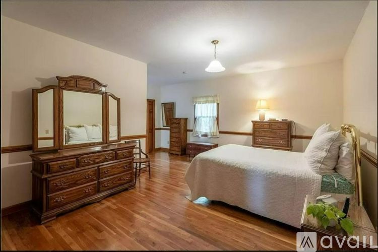 A bedroom with a large bed and a wooden dresser.