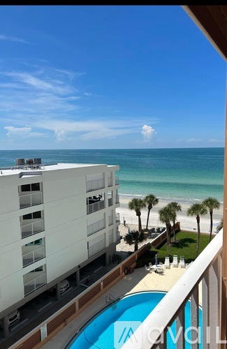 A view of a hotel balcony overlooking a pool and beach.