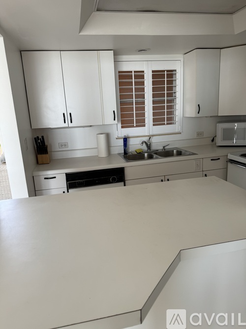 A kitchen with white cabinets and a white counter top.