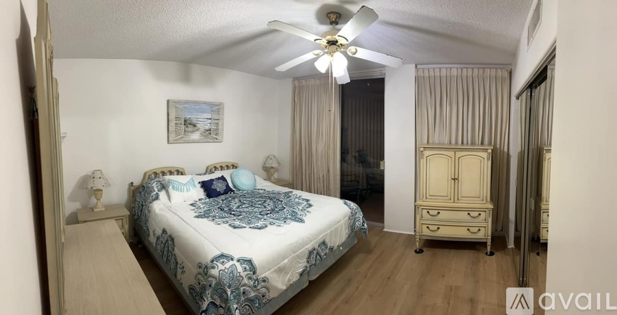 A bedroom with a bed, dresser, and a ceiling fan.