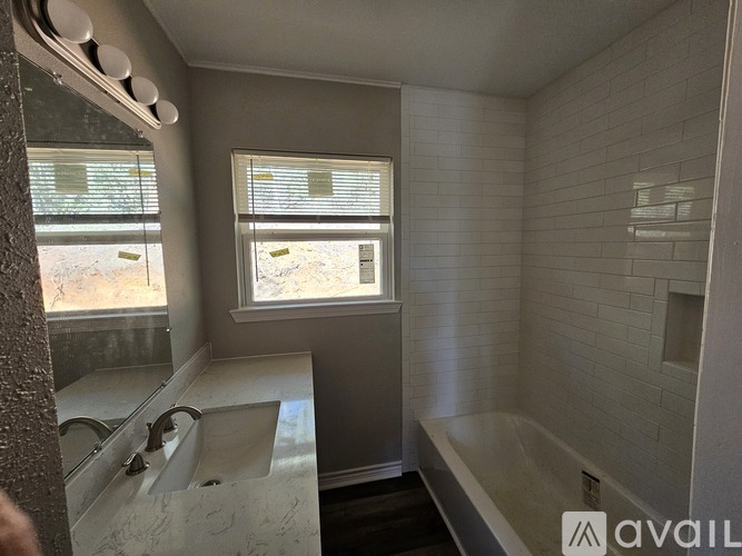 A bathroom with a tub, sink, and window.