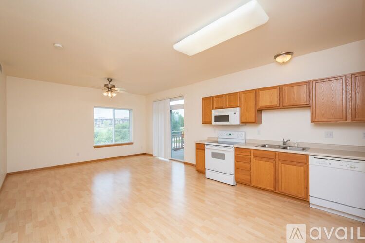 A kitchen with wooden cabinets and white appliances is available for rent.