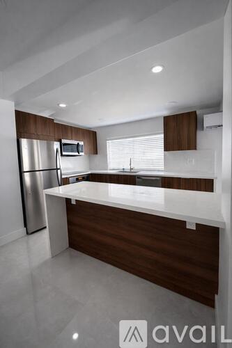 A modern kitchen with a white countertop and a stainless steel refrigerator.