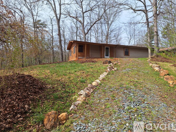 A wooden cabin is situated in a wooded area with a path leading to it.