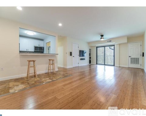 A room with wooden floors and a bar area with stools.