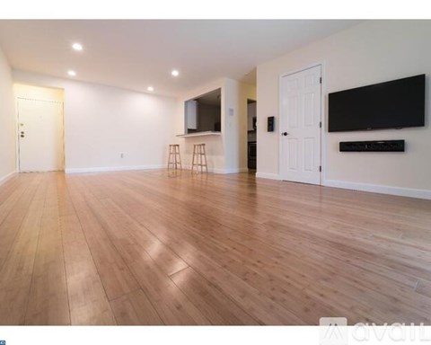 A spacious room with wooden flooring and white walls.