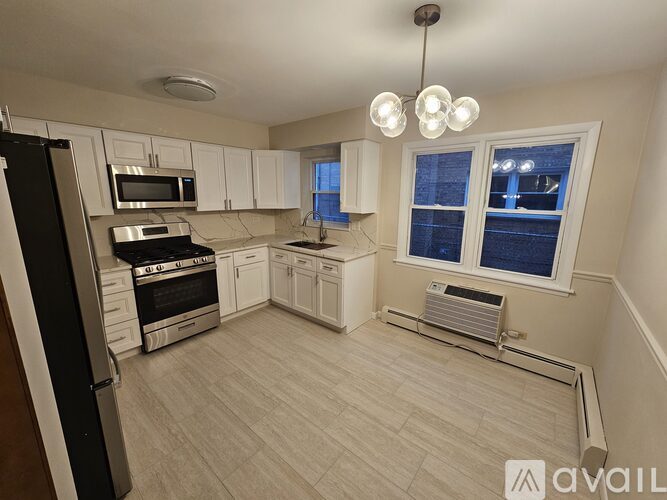 A kitchen with white cabinets and a black refrigerator.