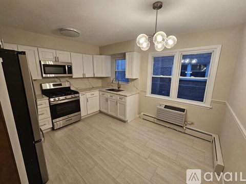 A kitchen with white cabinets and a black refrigerator.