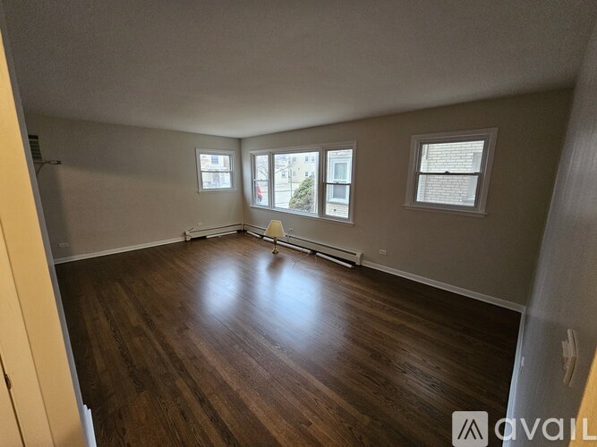 A room with wooden floors and three windows.