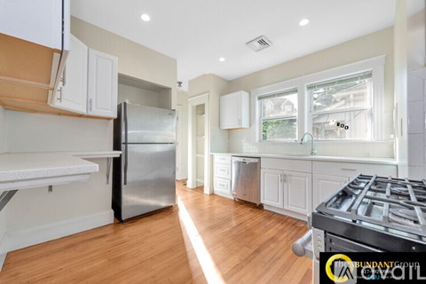 A kitchen with a stainless steel refrigerator and wooden floors.