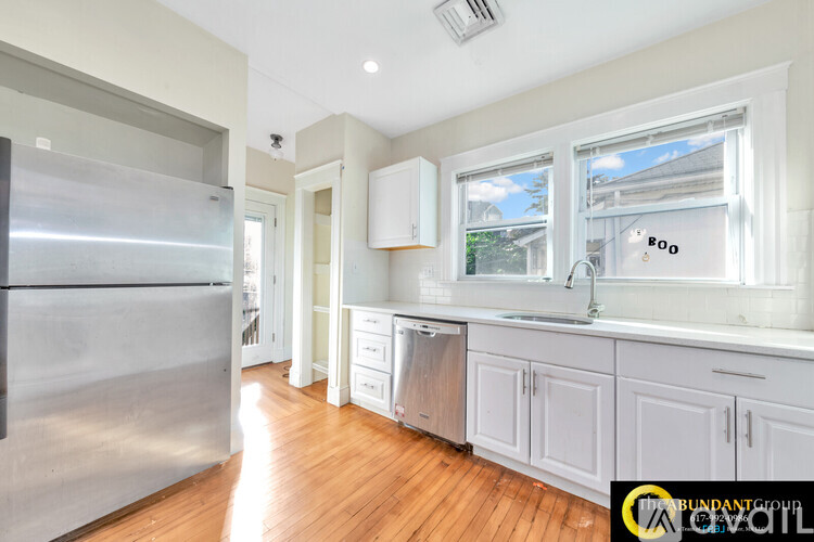 A kitchen with white cabinets and a stainless steel refrigerator.