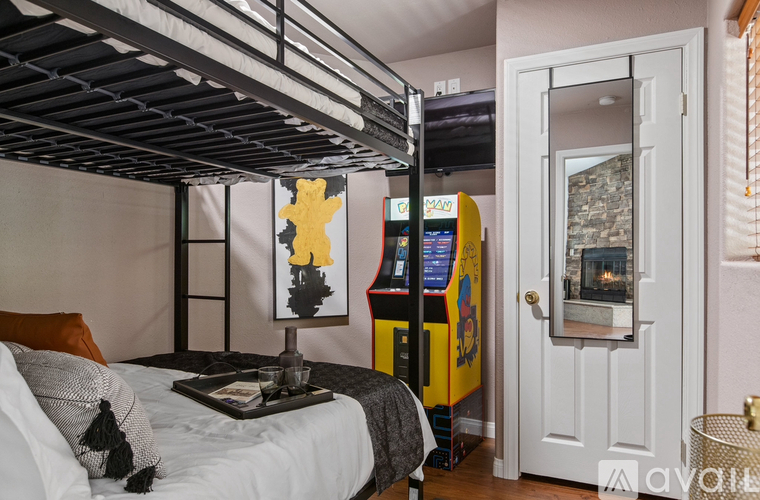 A bedroom with a bunk bed and a yellow arcade machine.